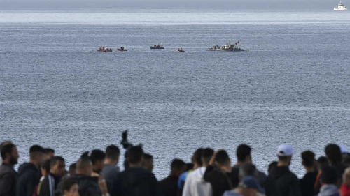 People look at a rescue boats arriving at the scene of a helicopter crash in the Mediterranean sea off the coast of the commune of Bouharoun in Tipasa province, about 30 kilometres west of Algiers in northern Algeria on December 16, 2020. (Photo by Ryad KRAMDI / AFP)