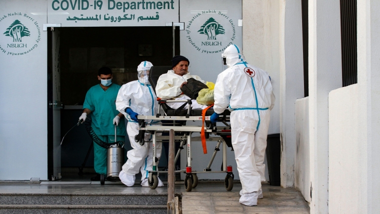 Members of the Lebanese Red Cross wearing hazmat suits, transfer an elderly coronavirus patient to the COVID-19 department of the Nabih Berri university hospital, in the southern Lebanese city of Nabatiyeh, on January 9, 2021. - Since the start of the Covid-19 pandemic, Lebanon has recorded nearly 200,000 cases including 1,537 deaths, according to health ministry figures. Health professionals have warned that the latest surge in cases risked causing catastrophe across Lebanon, which is already suffering from the aftermath of a devastating August explosion in Beirut and a dire economic crisis. (Photo by Mahmoud ZAYYAT / AFP) (Photo by MAHMOUD ZAYYAT/AFP via Getty Images)