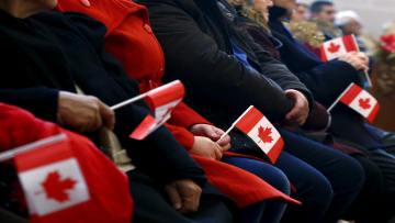 FILE PHOTO: Syrian refugees hold Canadian flags as they take part in a welcome service at the St. Mary Armenian Apostolic Church at the Armenian Community Centre of Toronto in Toronto, Ontario, Canada, December 11, 2015. REUTERS/Mark Blinch/File Photo
