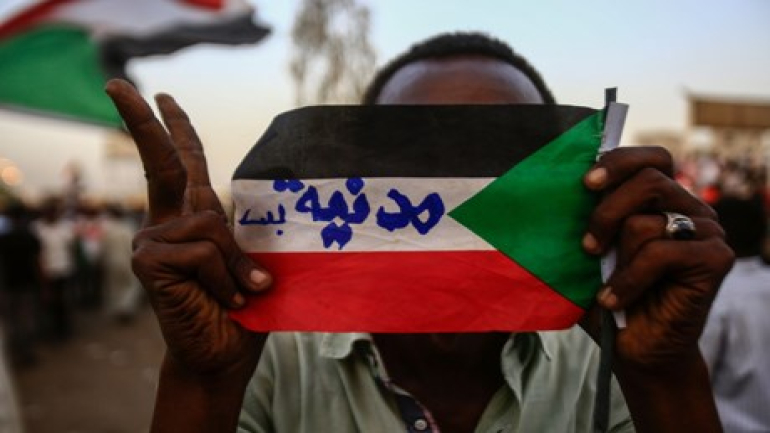 A Sudanese protester holds the national flag with writings reading in Arabic "Civilian Only" during a rally outside the army headquarters in Khartoum on May 2, 2019. - Sudan's prosecutor general ordered the questioning of deposed president Omar al-Bashir over money-laundering and "financing terrorism", as protesters staged a vast rally in Khartoum to demand a civilian government. (Photo by ASHRAF SHAZLY / AFP)
