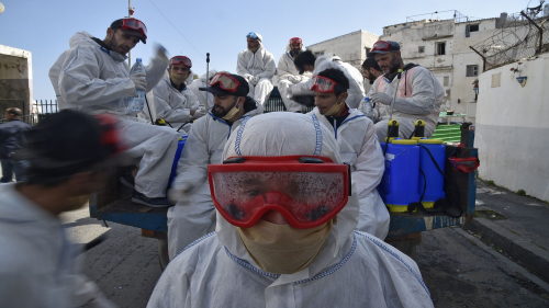 Municipal workers dressed in protective gear rest while on duty disinfecting a street during the COVID-19 coronavirus pandemic in the Bab el-Oued district of Algeria's capital Algiers on April 9, 2020. (Photo by RYAD KRAMDI / AFP) (Photo by RYAD KRAMDI/AFP via Getty Images)