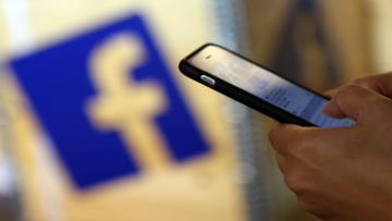 BERLIN, GERMANY - SEPTEMBER 12: A visitor uses a mobile phone in front of the Facebook logo at the #CDUdigital conference on September 12, 2015 in Berlin, Germany. The world's largest social media network was launched by Mark Zuckerberg and his Harvard College roommates in 2004, and had its initial public offering in February 2012. (Photo by Adam Berry/Getty Images)