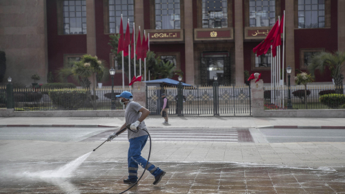 A worker disinfects a main avenue outside the parliament building in a bid to prevent the spread of coronavirus on Wednesday in Rabat, Morocco. The country imposed sudden, sweeping restrictions on travel.