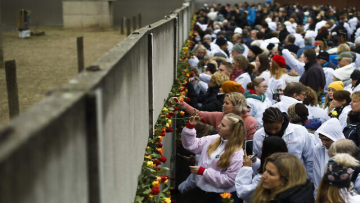 People stuck flowers in remains of the Berlin Wall during a commemoration ceremony to celebrate the 30th anniversary of the fall of the Berlin Wall at the Wall memorial site at Bernauer Strasse in Berlin, Saturday, Nov. 9, 2019. (AP Photo/Markus Schreiber)