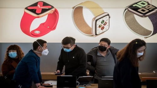 In this picture taken on March 11, 2020 an Apple staff (C) and customers wearing face masks as a preventive measure against the COVID-19 coronavirus are seen inside of an Apple shop in Beijing. - The number of fresh infections at the epicentre of China's COVID-19 coronavirus epidemic dropped to a new low on March 12 but the country imported more case from abroad. (Photo by NICOLAS ASFOURI / AFP)