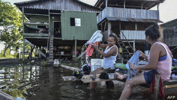 Women wash clothes at the Amazon river in Leticia, Colombia on May 13, 2020, amid the new coronavirus pandemic. - Colombia will increase the presence of military personnel on the Amazon border that shares with Brazil and Peru due to the COVID-19 outbreak hitting that helpless and poor region, and that has already reached the departmental prison. (Photo by Tatiana Alvarez / AFP)