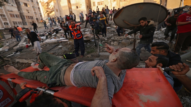 Palestinians carry one of survivers from under the rubble of a building, after it was struck by Israeli strikes, in Gaza City, May 16, 2021. - Israeli forces pummeled the densely populated Gaza Strip, the sixth day of bombardments on the Palestinian enclave controlled by Islamist group Hamas, which fired back rocket barrages. (Photo by MOHAMMED ABED / AFP)