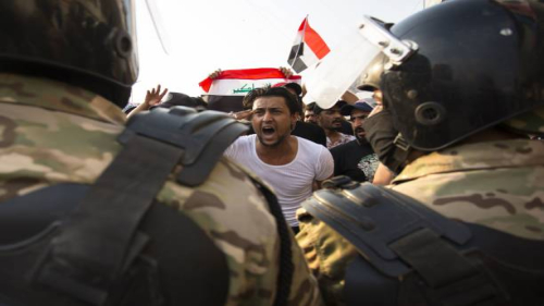 TOPSHOT - An Iraqi protestor gestures in front of security forces during a demonstration against state corruption, failing public services and unemployment, on October 2, 2019 in the southern city of Basra. - Popular protests multiplied across Iraq today as thousands of demonstrators braved live fire and tear gas in rallies that have left seven dead in the past 24 hours. (Photo by Hussein FALEH / AFP) (Photo by HUSSEIN FALEH/AFP via Getty Images)