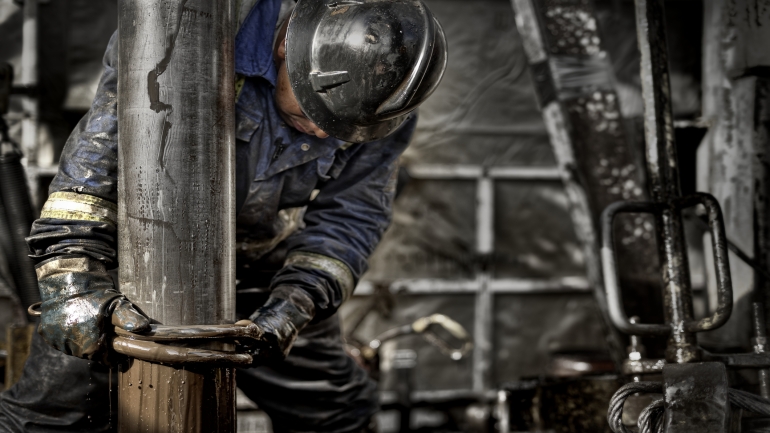 Oil Rig Worker wearing his safety gear working on the muddy drill floor