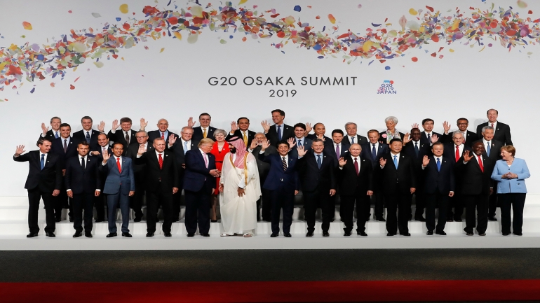 US President Donal Trump (C-L) chats with Saudi Arabia's Crown Prince Mohammed bin Salman (C-R) as other leaders wave during a family photo at the G20 Summit in Osaka on June 28, 2019. (Photo by KIM KYUNG-HOON / POOL / AFP)