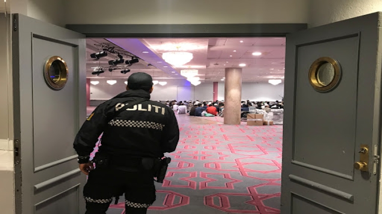 A Norwegian police officer looks on as people gather before morning prayer in Thon Oslofjord hotel in Sandvika, Norway August 11, 2019. REUTERS/Lefteris Karagiannopoulos